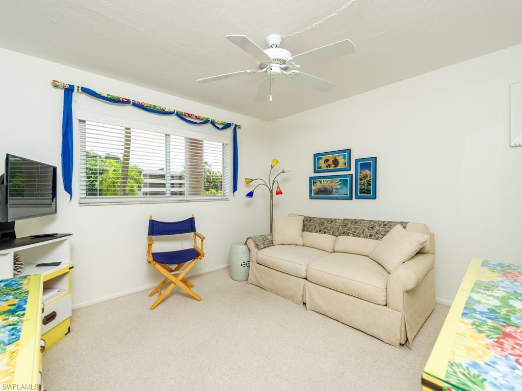 Living area with light colored carpet and a ceiling fan