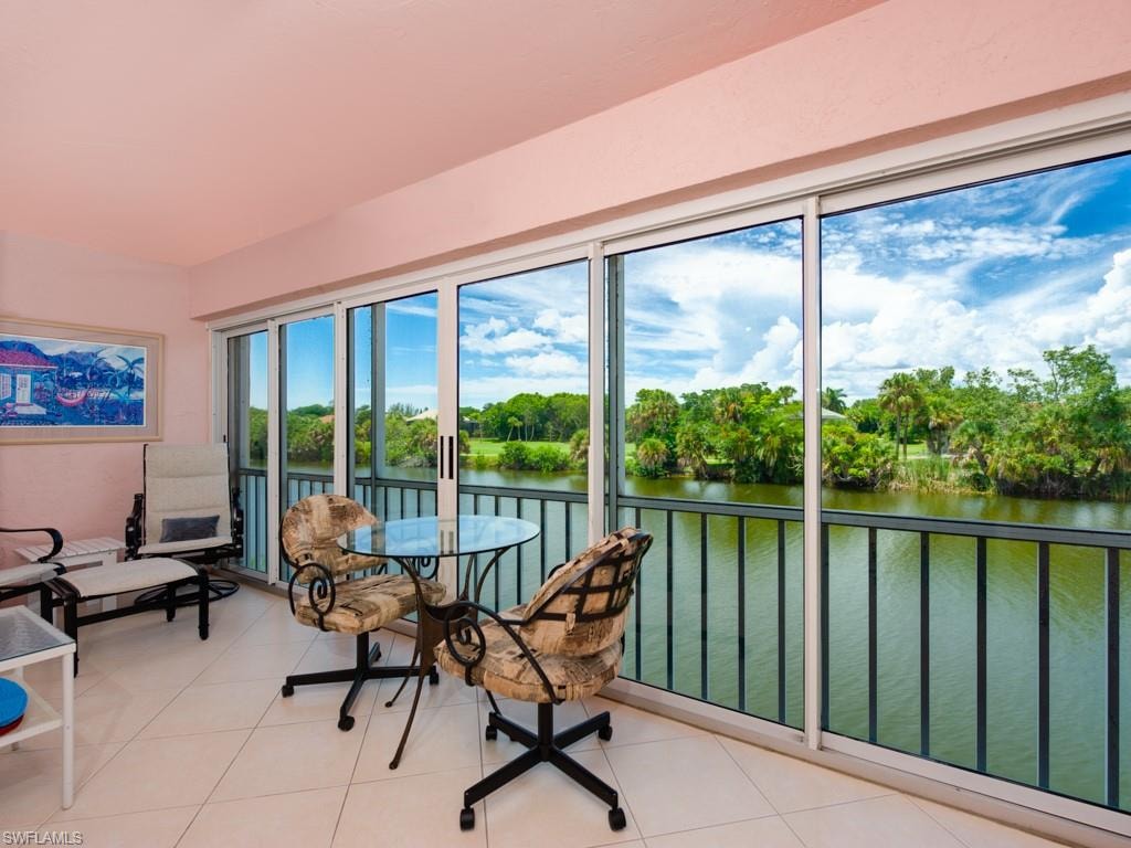 Sunroom featuring a water view and view of wooded area