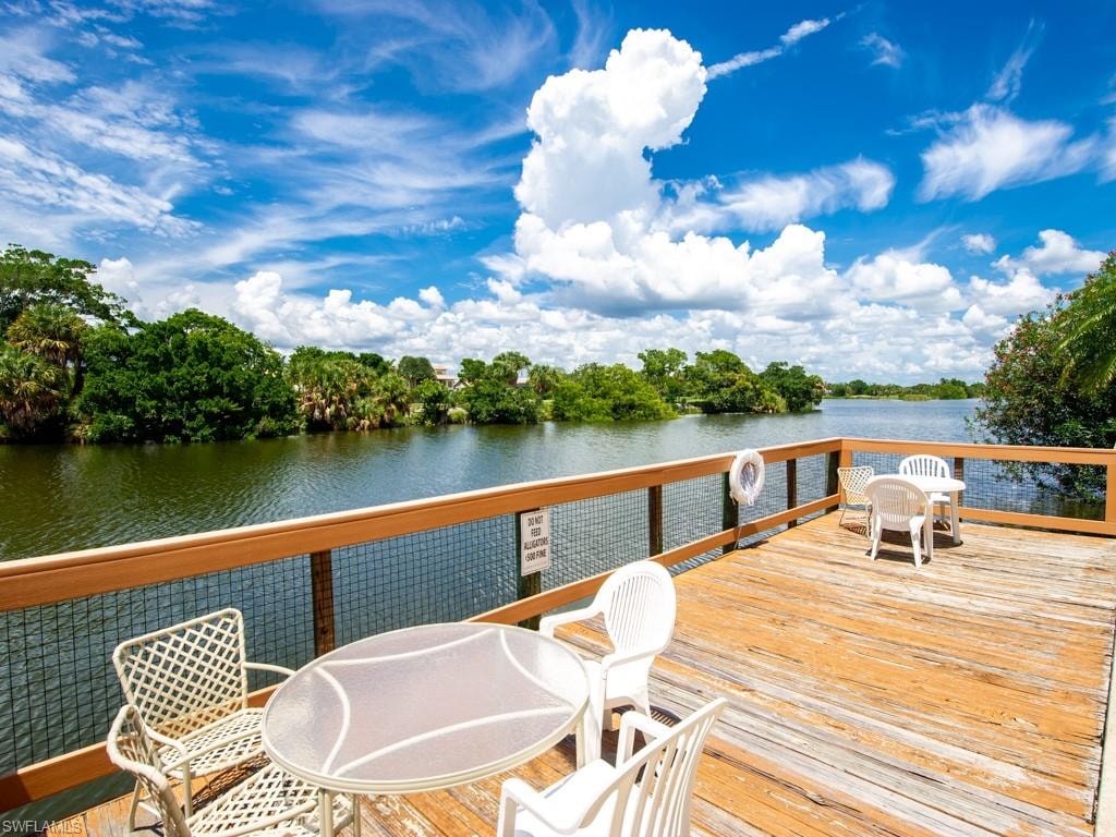 Dock with outdoor dining area, view of scattered trees, and a deck with water view