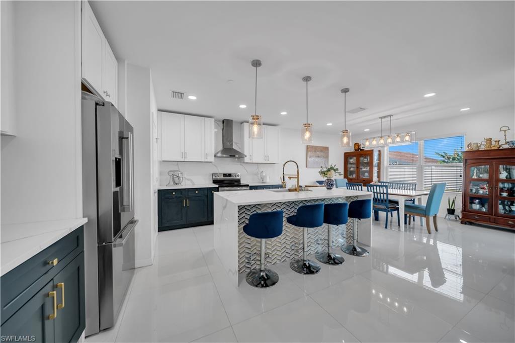 Kitchen with appliances with stainless steel finishes, pendant lighting, a breakfast bar area, light tile patterned floors, and recessed lighting