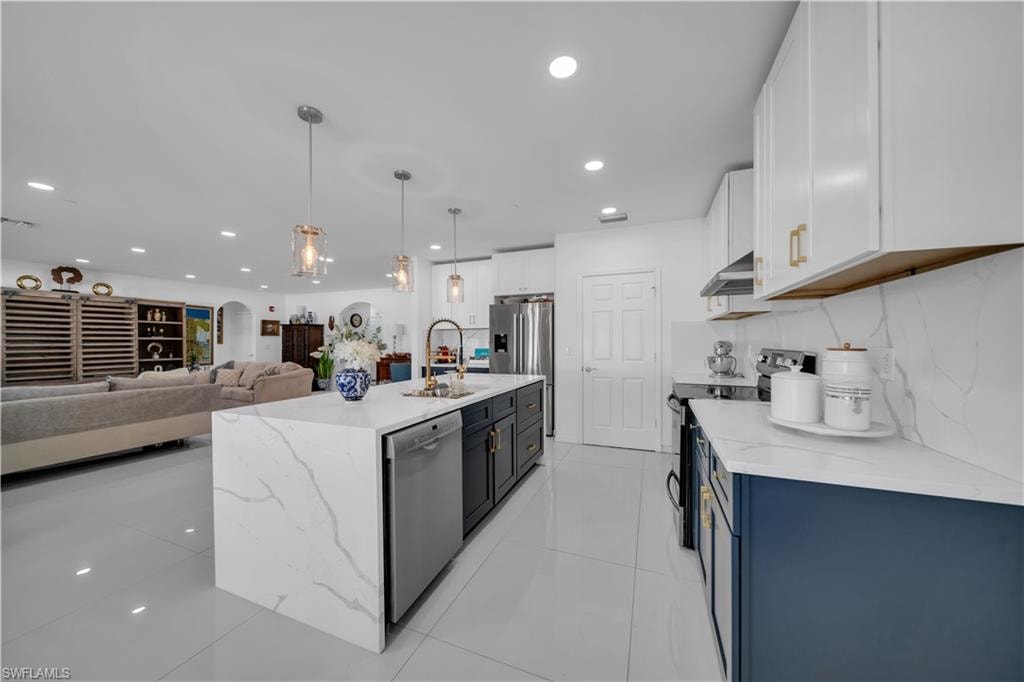 Kitchen with light tile patterned floors, light stone countertops, open floor plan, hanging light fixtures, and recessed lighting