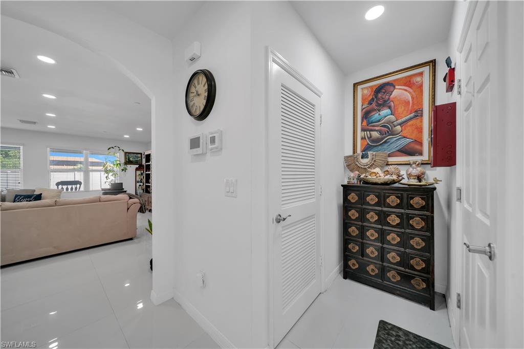 Hall featuring arched walkways, recessed lighting, and light tile patterned floors