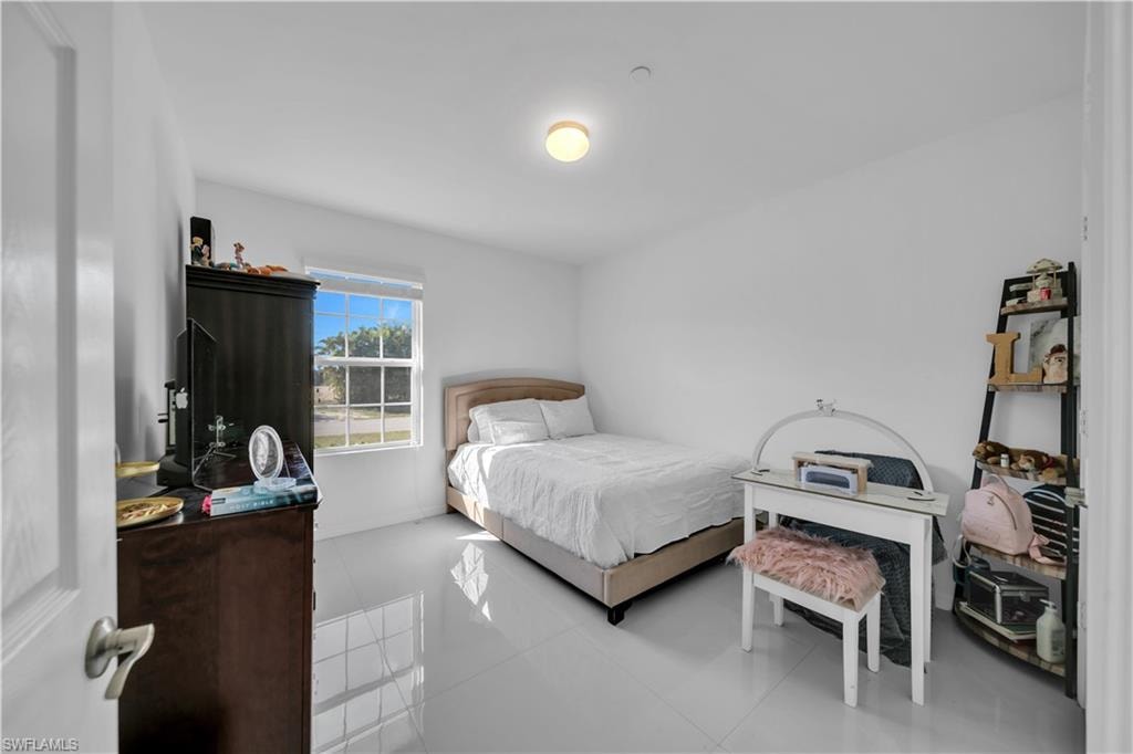Bedroom with a desk, light tile patterned floors, and a closet