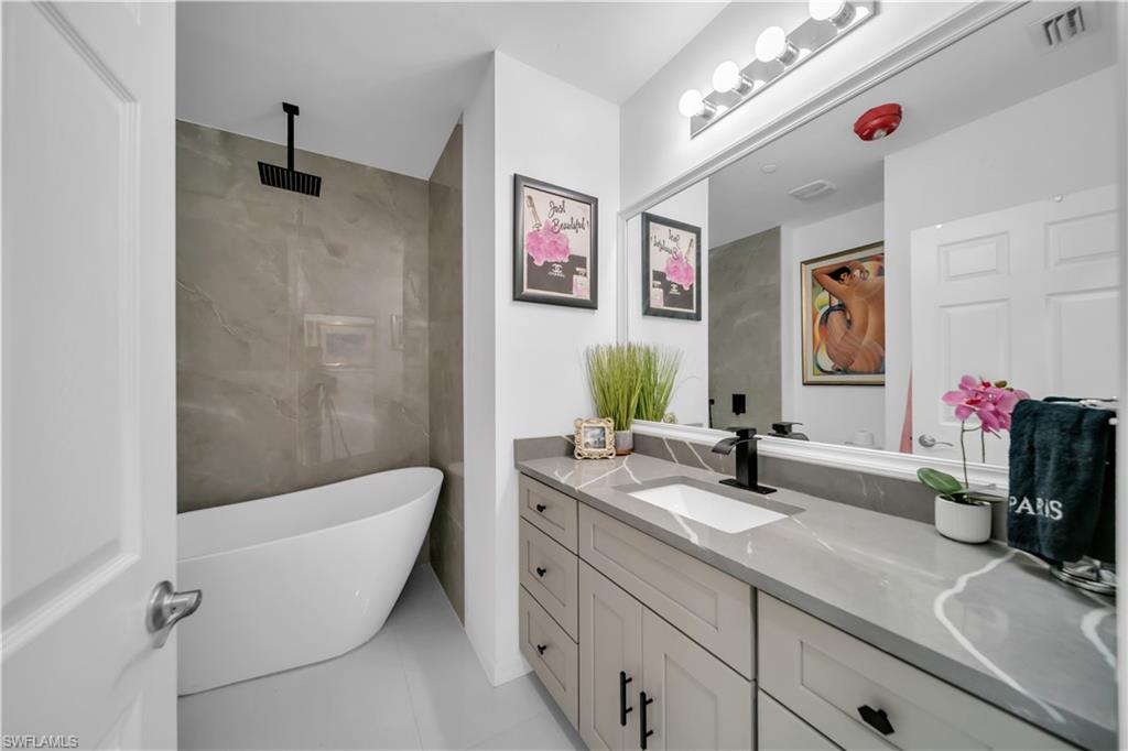 Full bath with a freestanding bath, tiled shower, vanity, and tile walls