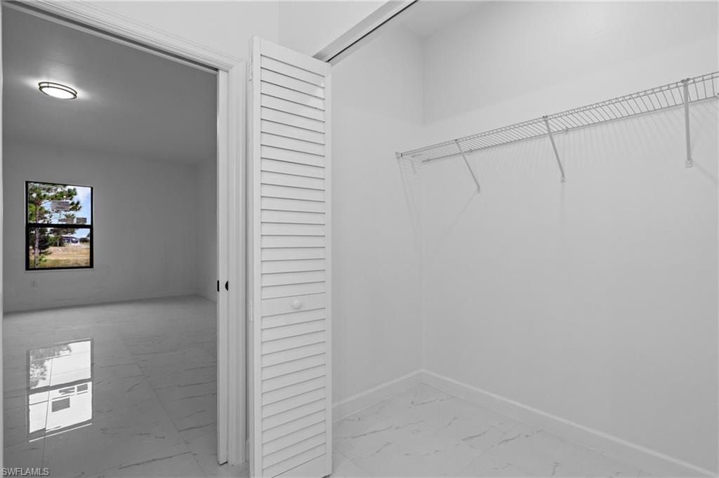 Spacious closet featuring light marble finish floors