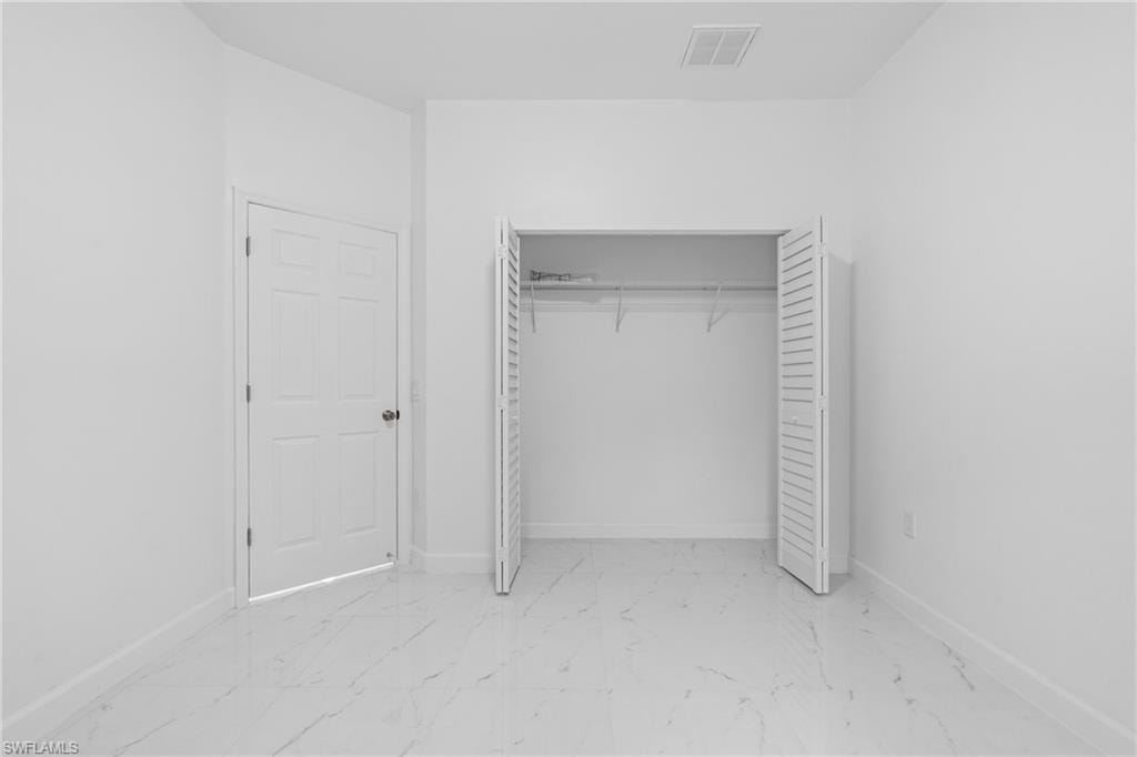 Unfurnished bedroom with light marble finish flooring and a closet