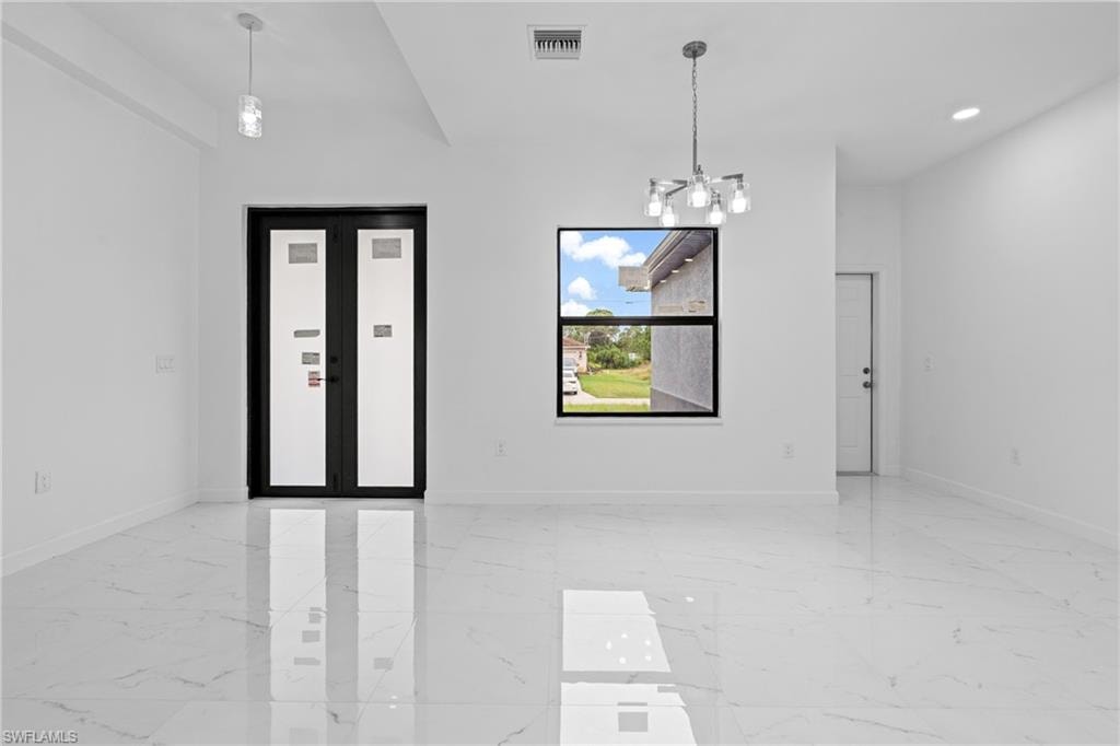 Empty room featuring light marble finish floors, a chandelier, and recessed lighting
