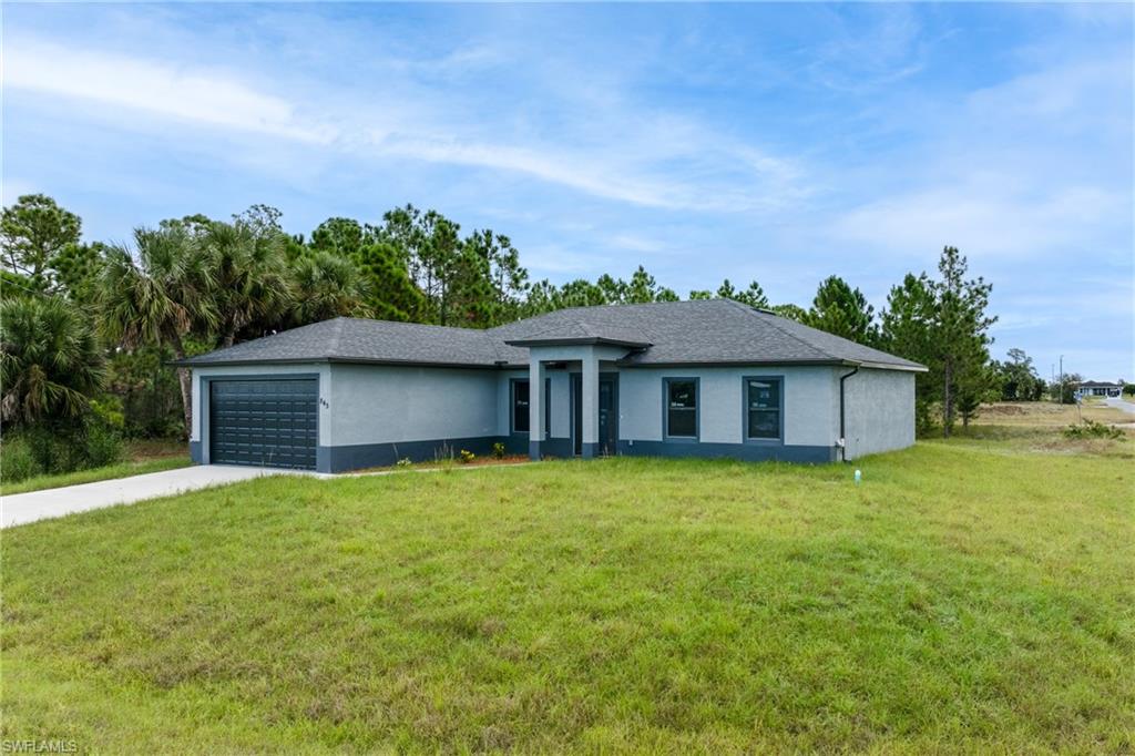 View of front of property featuring stucco siding, a front lawn, driveway, and an attached garage