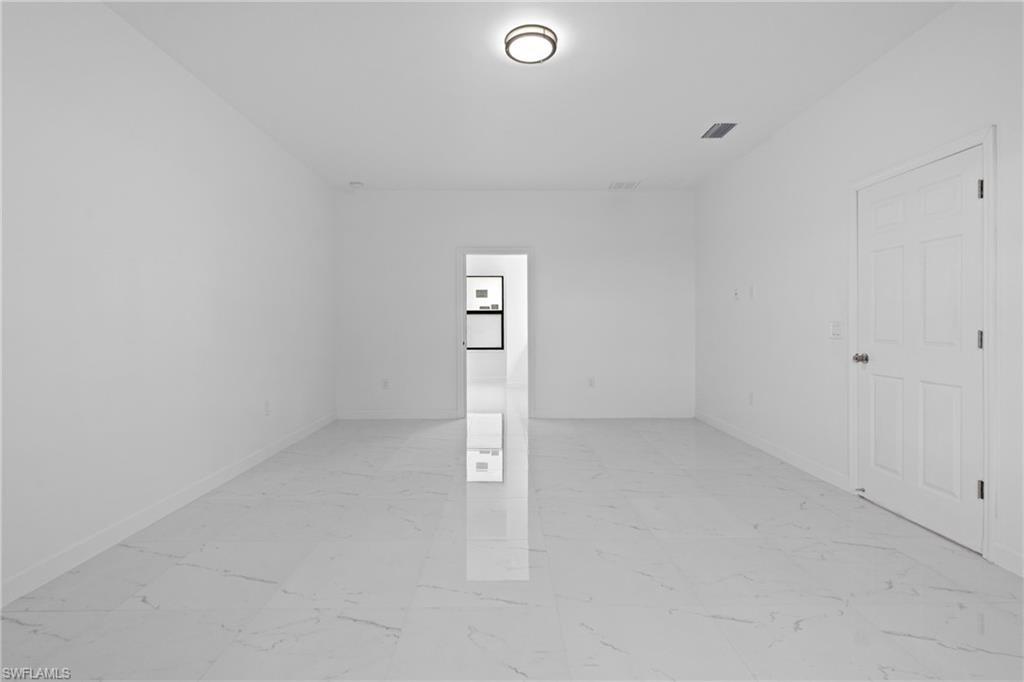 Spare room featuring light marble finish floors and baseboards