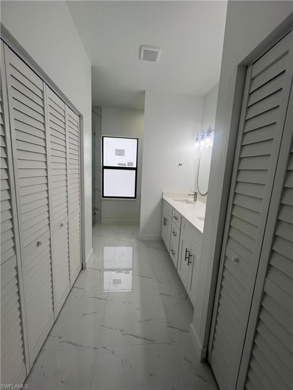 Kitchen with a kitchen island, stainless steel appliances, white cabinetry, light marble finish flooring, and recessed lighting