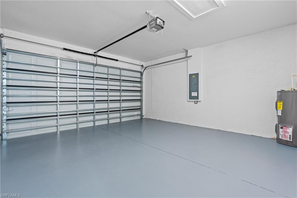 Garage with electric panel, water heater, and a garage door opener