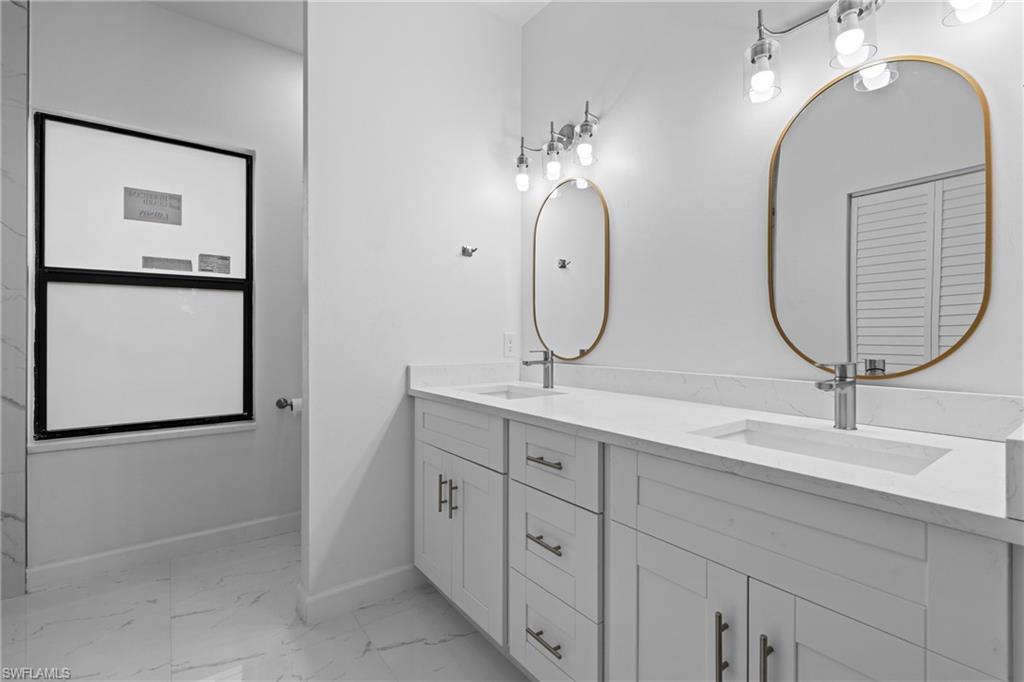Full bath with light marble finish flooring and double vanity