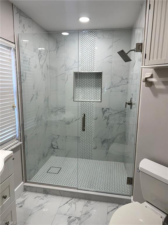 Bathroom with marble finish flooring, a marble finish shower, recessed lighting, and vanity