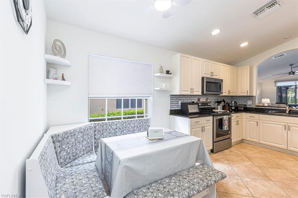 Kitchen featuring a ceiling fan, open shelves, appliances with stainless steel finishes, light tile patterned floors, and backsplash