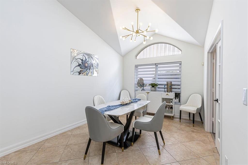 Dining space featuring a chandelier, light tile patterned floors, and high vaulted ceiling