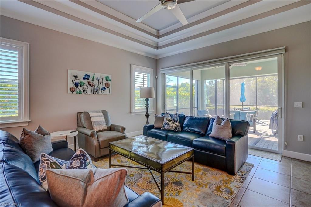 Living area featuring a raised ceiling, tile patterned flooring, and a ceiling fan