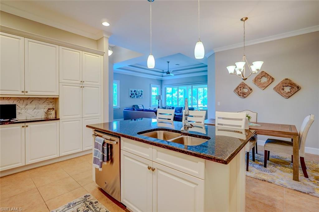 Kitchen with white cabinetry, crown molding, tasteful backsplash, dark stone counters, and open floor plan