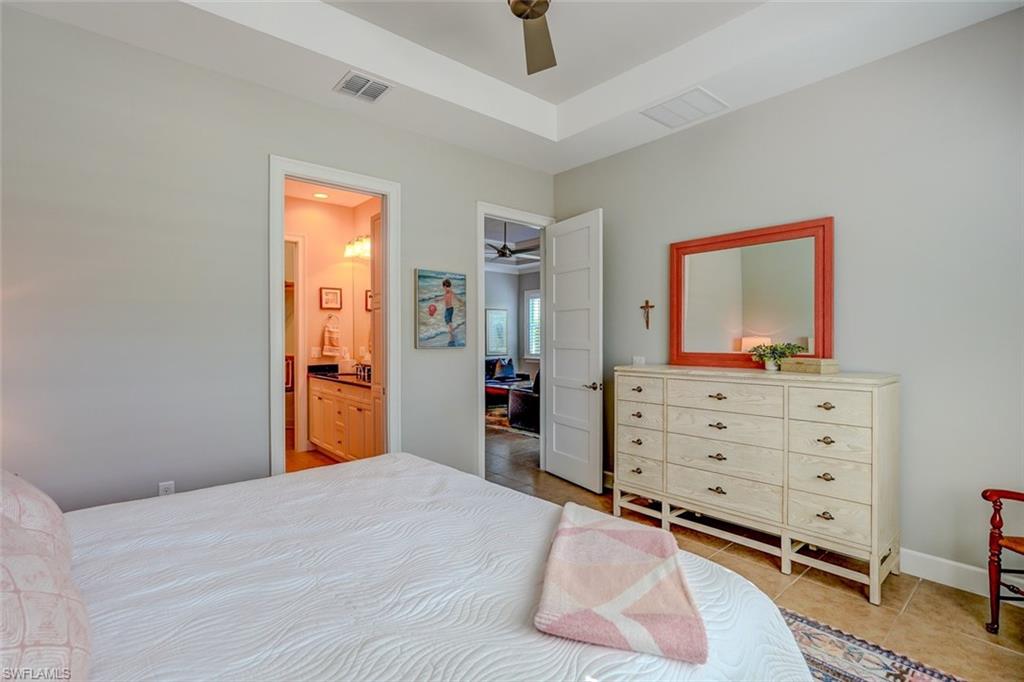 Bedroom with light tile patterned floors, ceiling fan, and ensuite bathroom