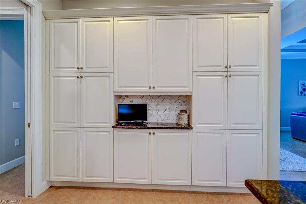 Kitchen featuring backsplash, white cabinets, dark stone counters, and light tile patterned floors