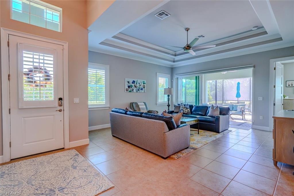 Living area with plenty of natural light, light tile patterned floors, a tray ceiling, and ceiling fan