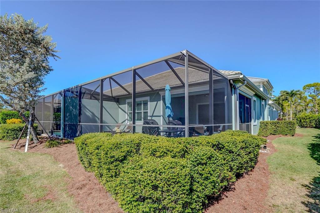 Back of property featuring a lanai, a sunroom, and a lawn