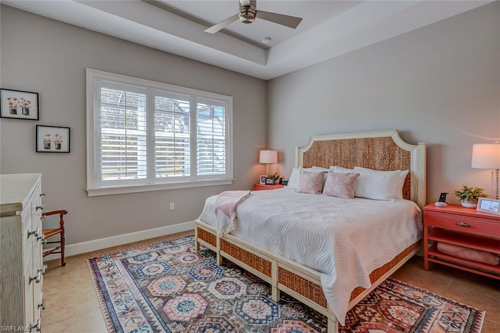 Bedroom featuring ceiling fan, light tile patterned floors, and a raised ceiling