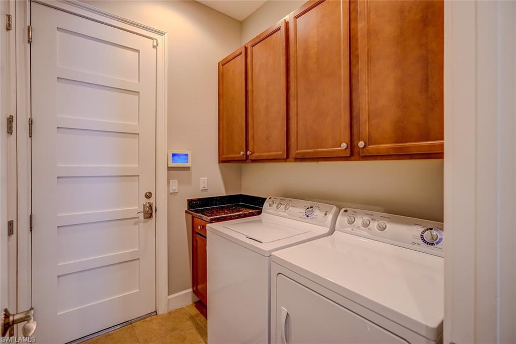 Laundry area featuring cabinet space, washing machine and clothes dryer, and light tile patterned flooring