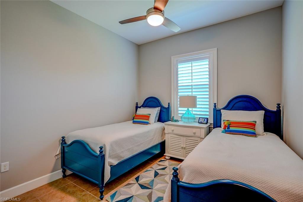 Tiled bedroom featuring a ceiling fan and baseboards
