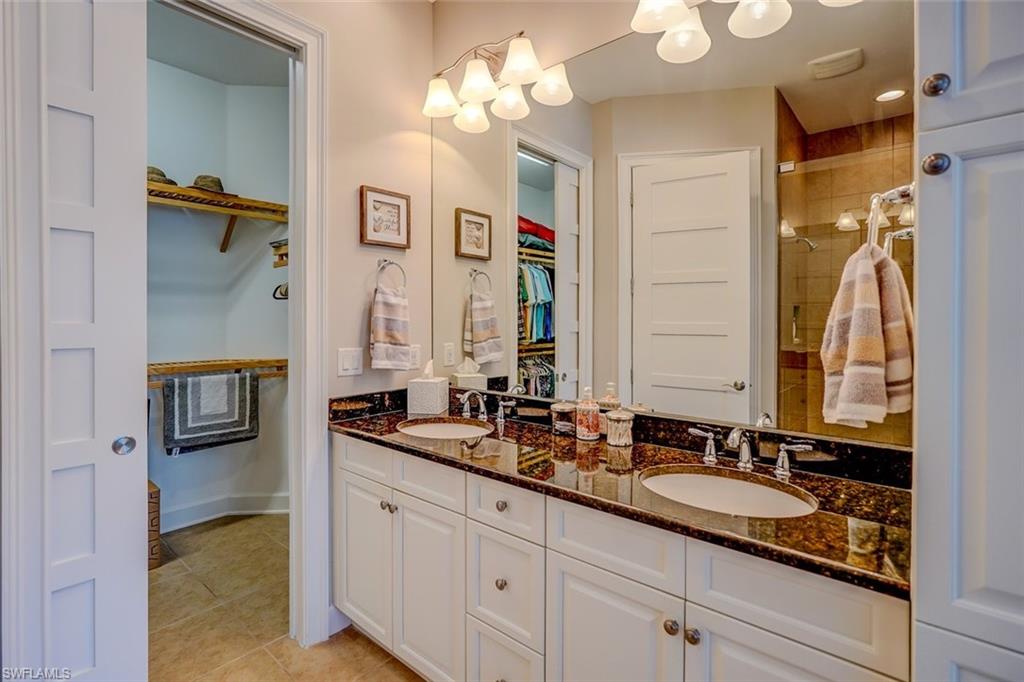 Full bath featuring a spacious closet, light tile patterned floors, double vanity, and a stall shower