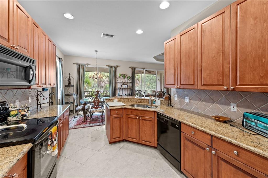 Kitchen featuring decorative backsplash, black appliances, light stone counters, a peninsula, and recessed lighting