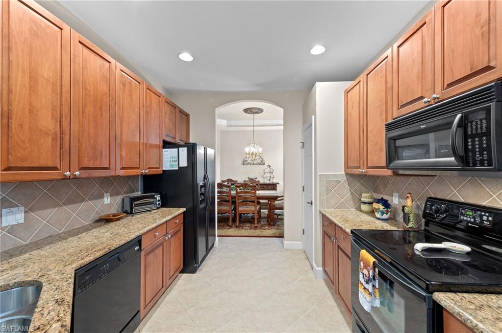 Kitchen with black appliances, tasteful backsplash, light stone countertops, brown cabinets, and recessed lighting