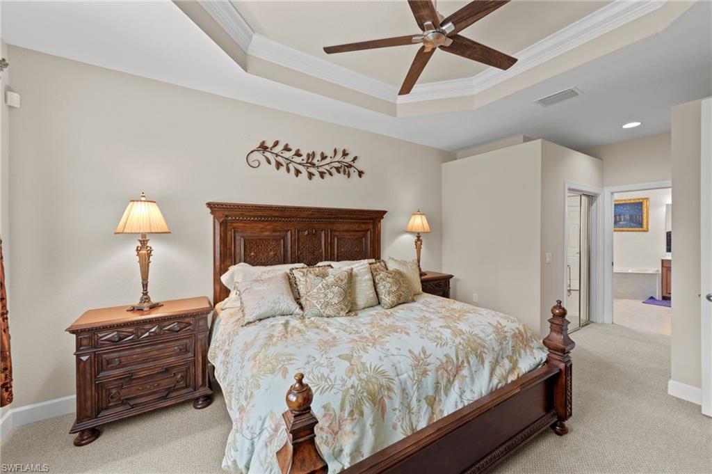 Bedroom featuring a raised ceiling, light colored carpet, ornamental molding, ceiling fan, and a closet