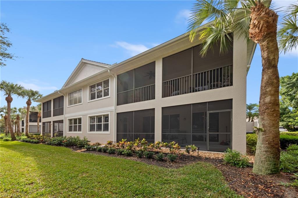 Back of property with a sunroom, stucco siding, and a lawn