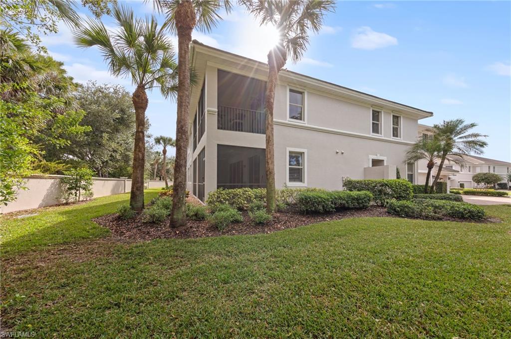Rear view of property with a sunroom, stucco siding, a lawn, and a balcony