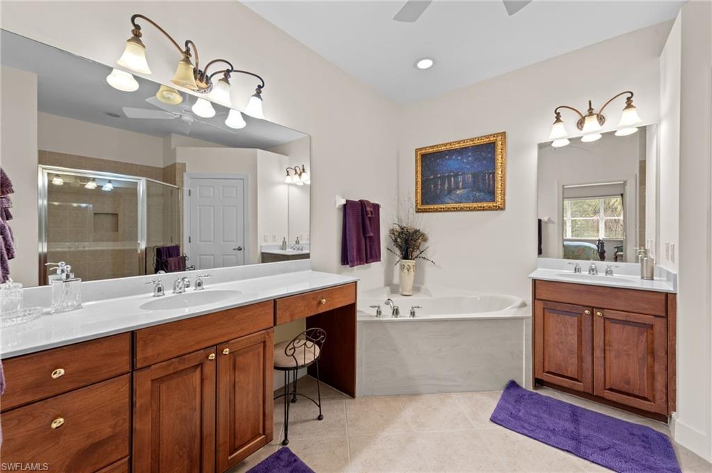 Full bath with a stall shower, two vanities, a garden tub, light tile patterned flooring, and ceiling fan