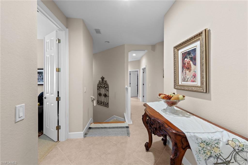 Hall with light tile patterned floors, arched walkways, recessed lighting, and a textured wall