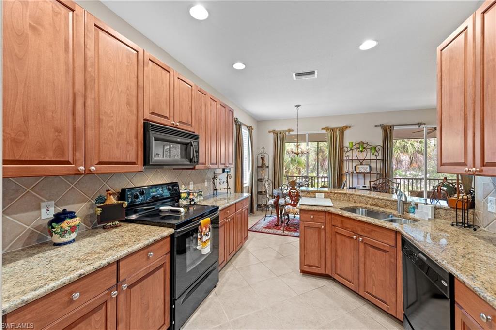Kitchen featuring black appliances, tasteful backsplash, light stone countertops, a peninsula, and recessed lighting