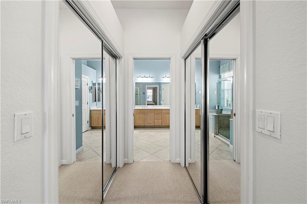 Hallway featuring a textured wall, light carpet, and light tile patterned flooring