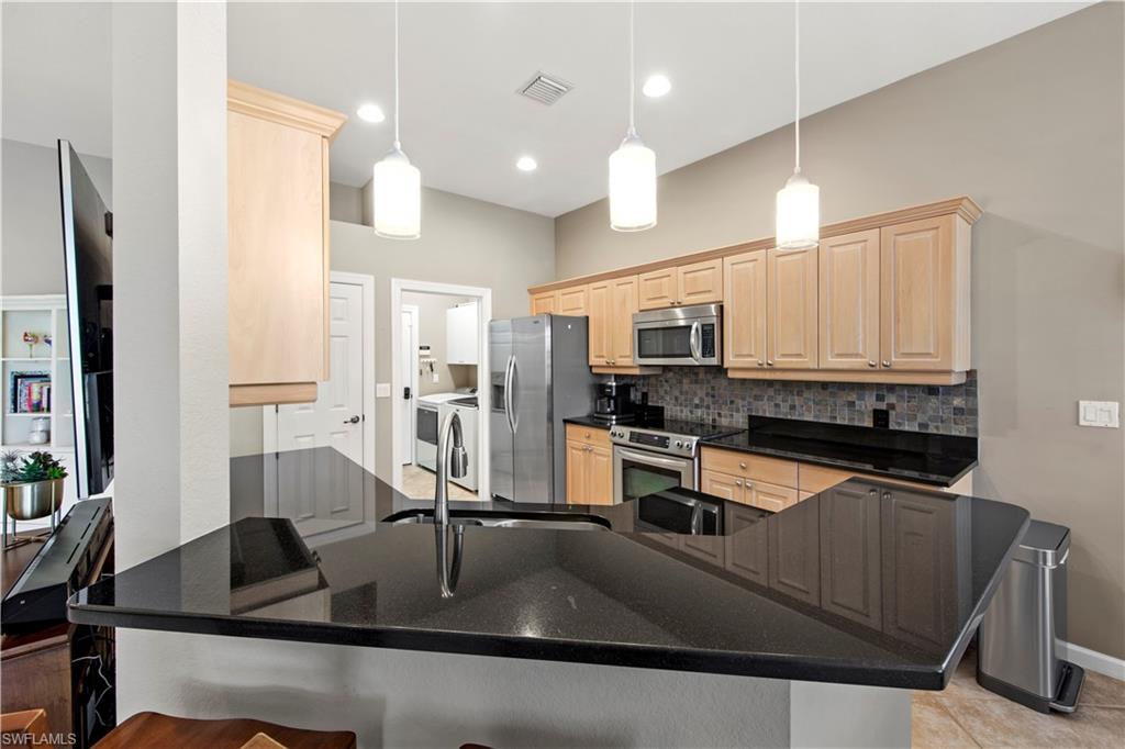 Kitchen featuring light brown cabinets, decorative light fixtures, decorative backsplash, and recessed lighting