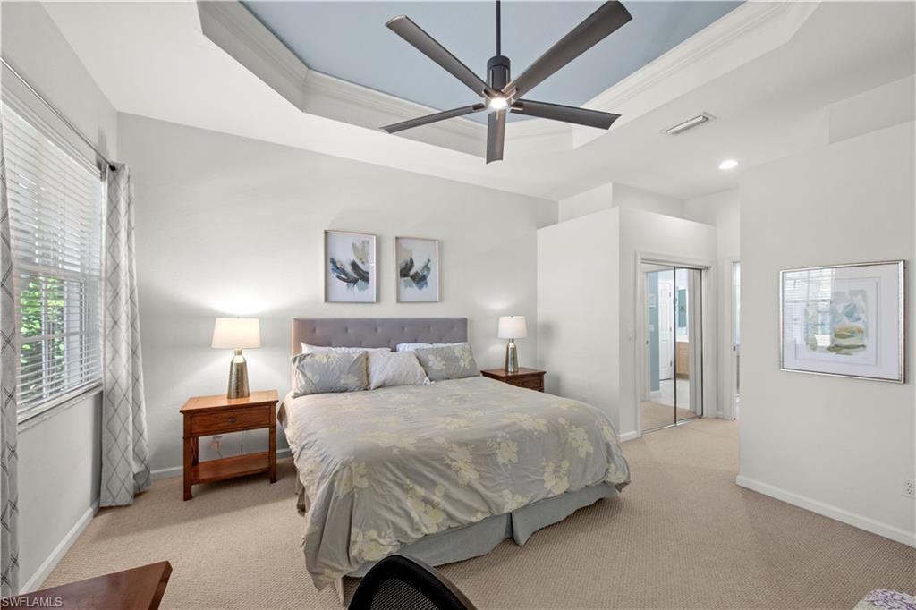 Bedroom featuring a raised ceiling, ornamental molding, light colored carpet, and a closet