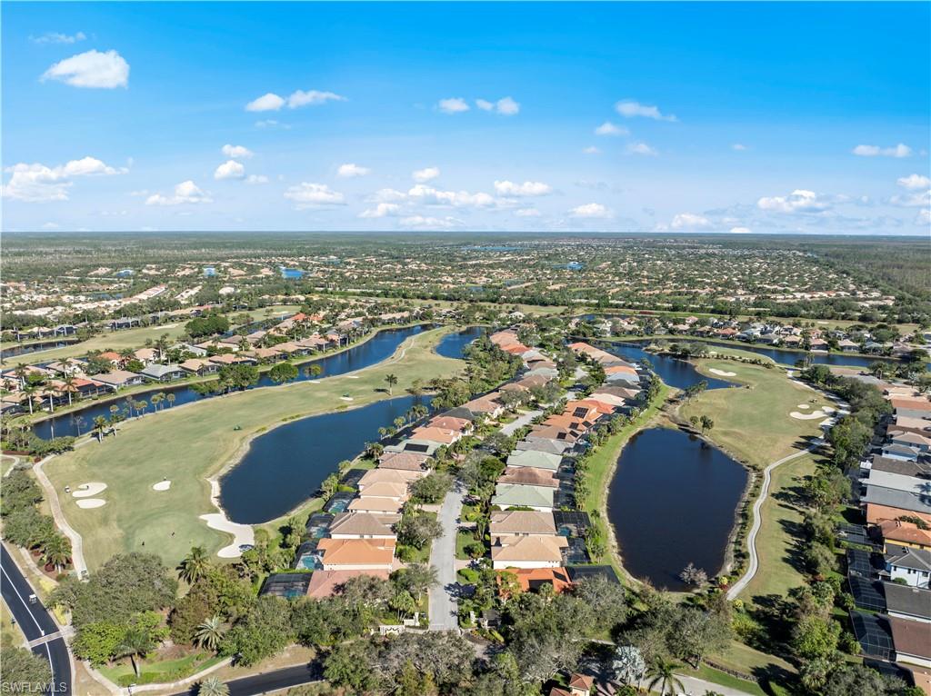 Aerial view of property and surrounding area featuring nearby suburban area, a golf club, and a large body of water