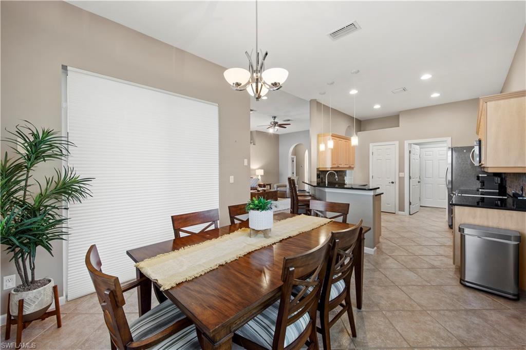 Dining space with light tile patterned floors, arched walkways, ceiling fan, recessed lighting, and a chandelier