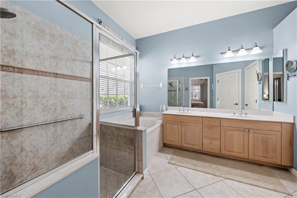Full bath featuring a shower stall, double vanity, light tile patterned floors, and a garden tub