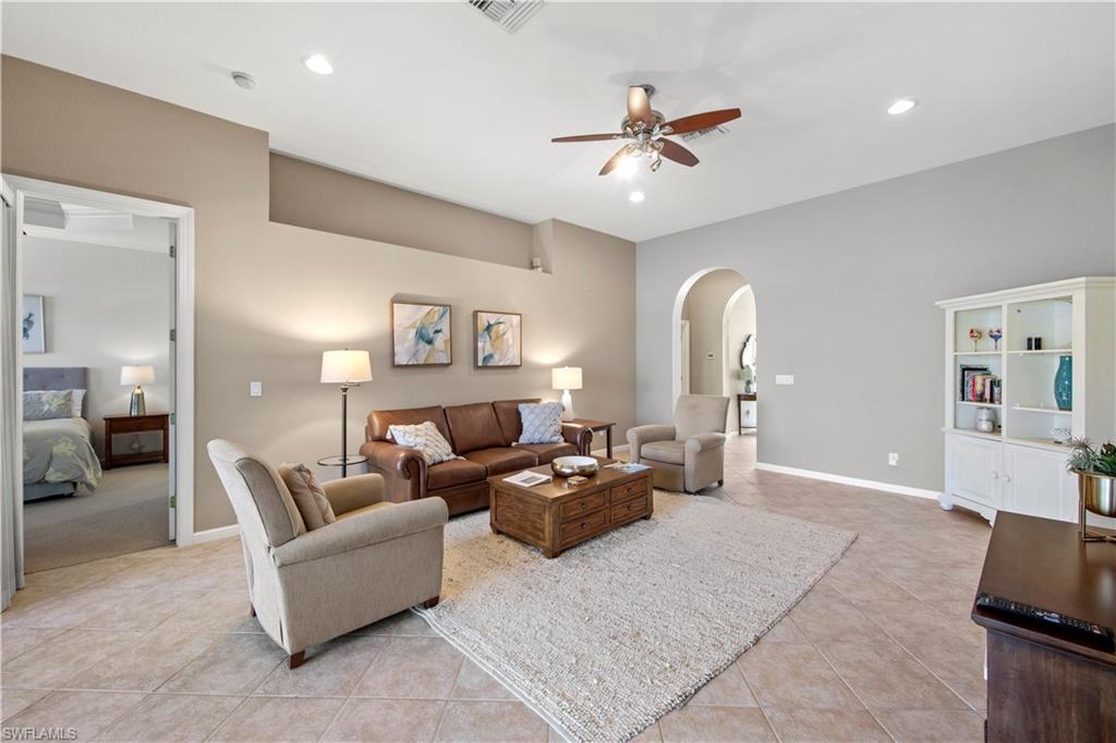 Living room with light tile patterned flooring, arched walkways, recessed lighting, and a ceiling fan