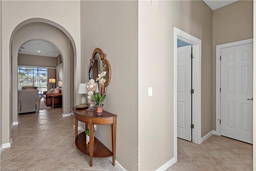Hallway with arched walkways and light tile patterned floors