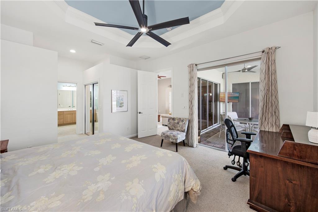 Bedroom featuring a tray ceiling, access to outside, light colored carpet, a closet, and a desk