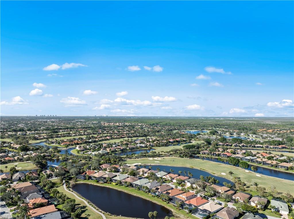 Aerial view of property and surrounding area featuring nearby suburban area, a large body of water, and a local golf course