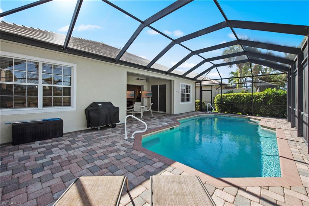 Swimming pool with a patio area, a sunroom, glass enclosure, grilling area, and ceiling fan