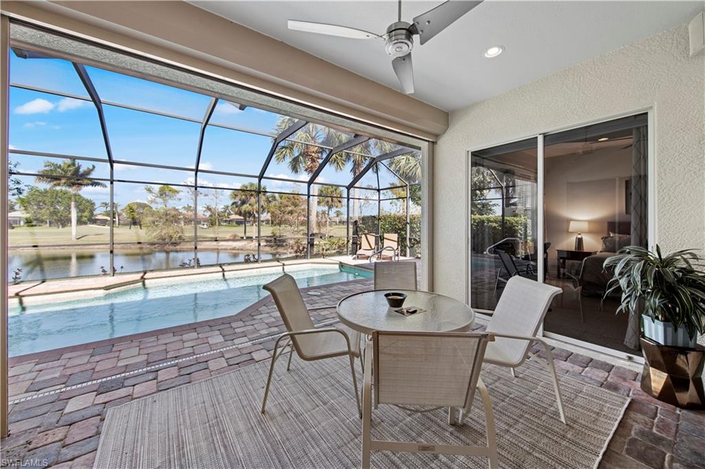 View of patio with an outdoor pool, glass enclosure, a ceiling fan, a sunroom, and a water view