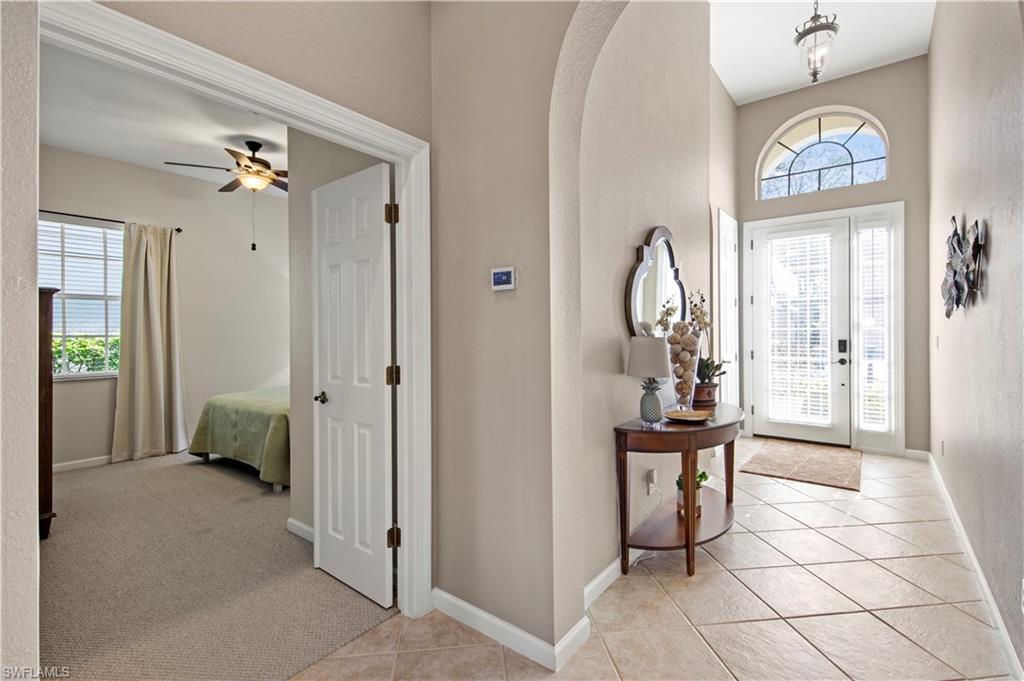 Foyer featuring light tile patterned floors, light colored carpet, arched walkways, and a towering ceiling